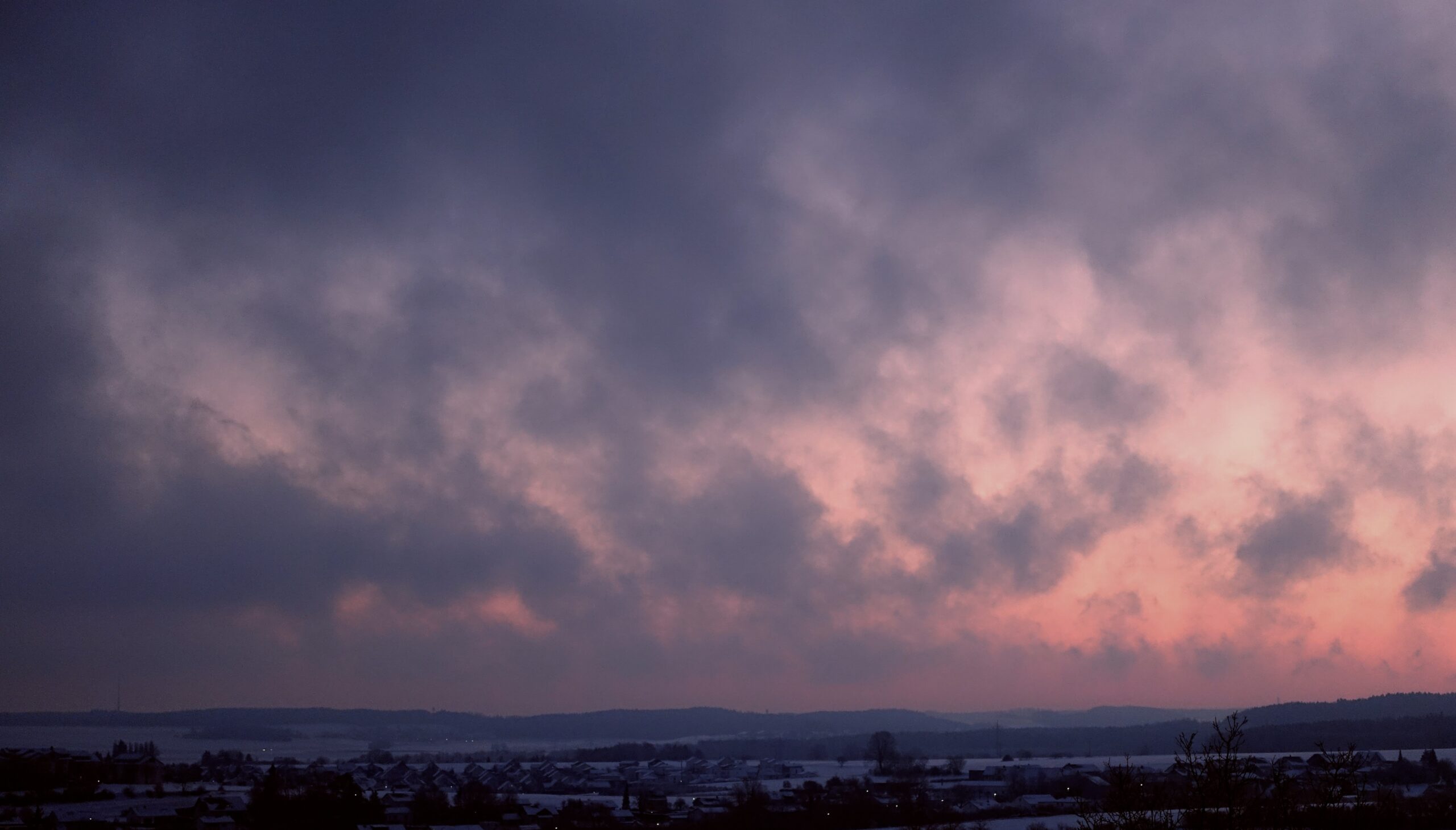 Sonnenuntergang hinter Wolken in Winterlandschaft