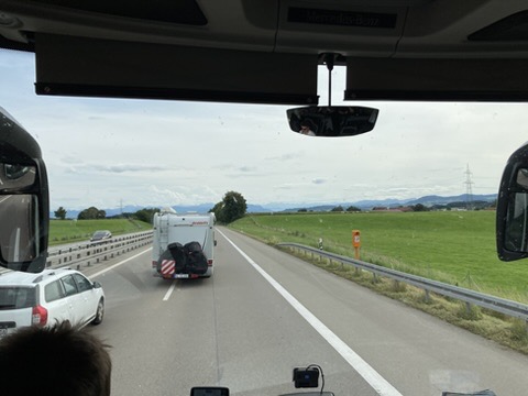 Assisireise Autobahn Ein Wohnmobil auf der Autobahn rechts und links grüne Landschaft, im HIntergrund die Berge.