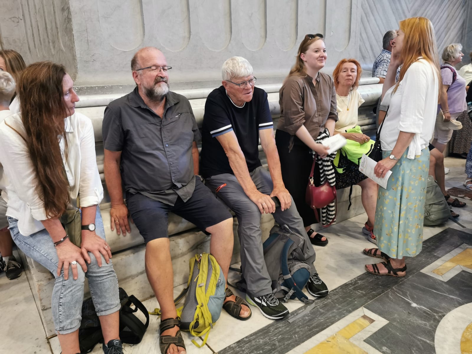 Eine Gruppe von Personen sitzt an einer der Säulen im Petersdom.