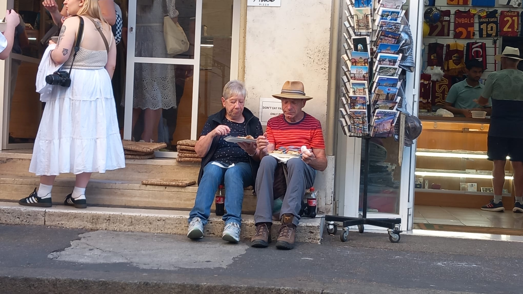 Zwei Personen die vor einem Gebäude sitzen und essen