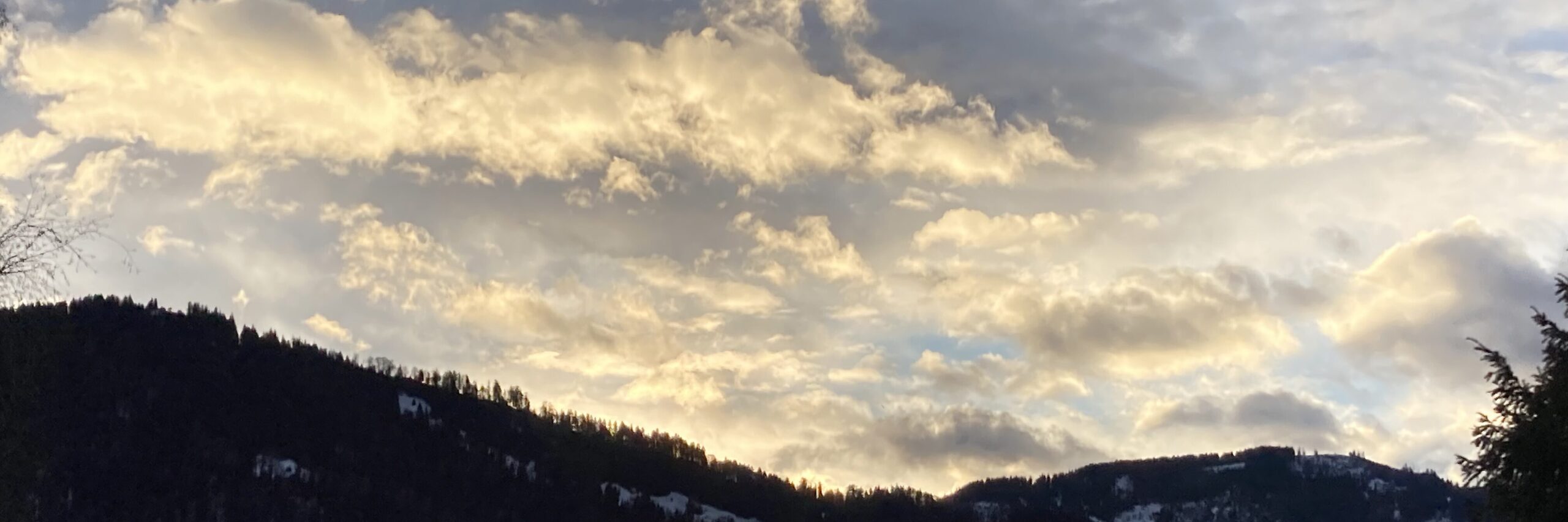 Morgenstimmung über dem See. Die Sonne färbt die Woken in einem hellen gelb.